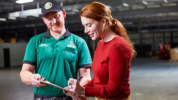 ODFL driver assisting a customer with shipping paperwork in a warehouse setting.